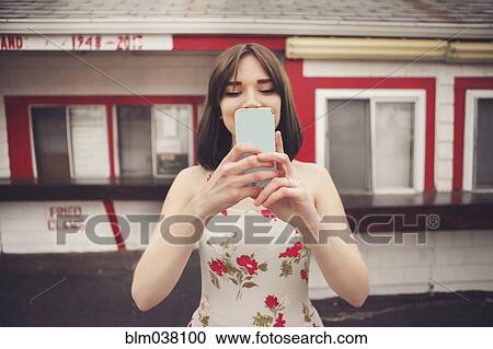 Stock Image - Caucasian woman taking selfie with cell phone. Fotosearch