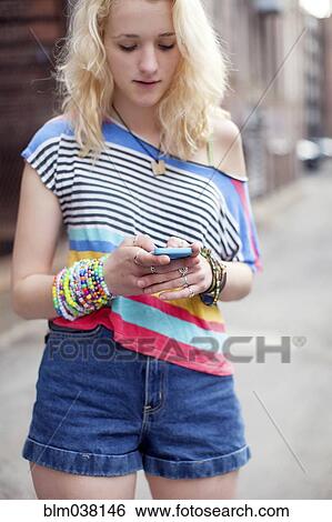 Stock Photograph - Caucasian woman using cell phone on city sidewalk. Fotosearch