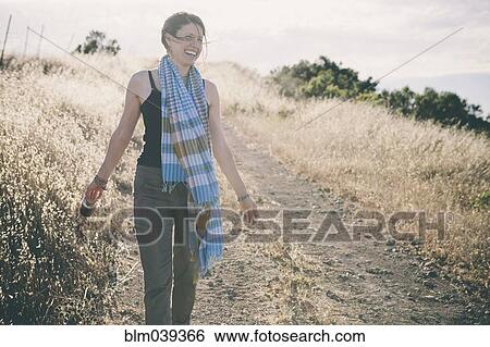 Caucasian woman walking on rural dirt road View Large Photo Image Stock Photograph - Caucasian woman walking on rural dirt road. Fotosearch