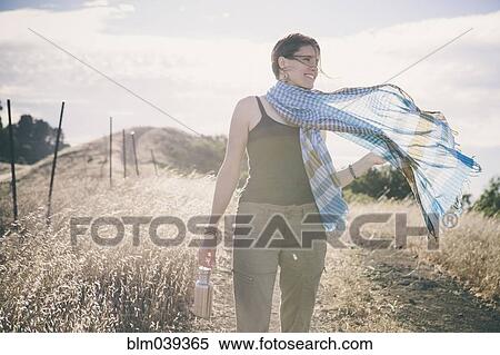 Stock Photography - Caucasian woman walking on rural dirt road. Fotosearch