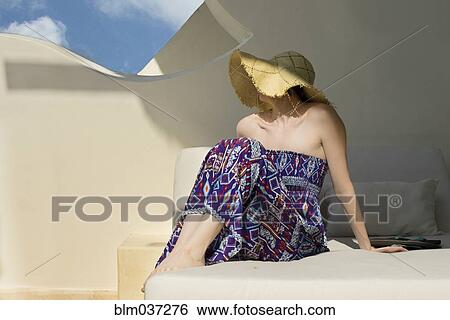 Stock Photograph - Caucasian woman wearing sun hat in cabana. Fotosearch