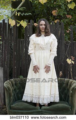 Caucasian woman wearing vintage gown standing on sofa View Large Photo Image Stock Image - Caucasian woman wearing vintage gown standing on sofa. Fotosearch