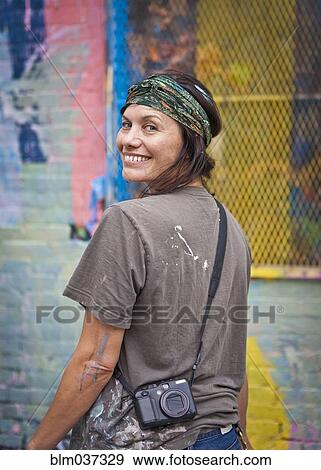 Stock Photo - Caucasian woman with paint-splattered shirt smiling. Fotosearch