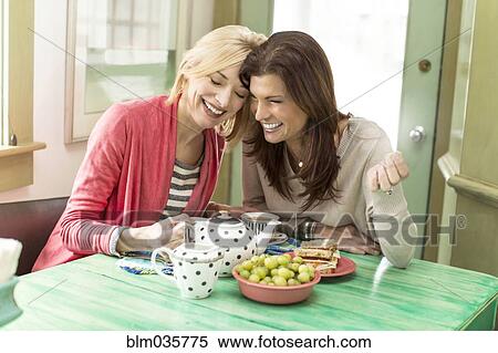 Stock Photography - Caucasian women drinking tea laughing. Fotosearch