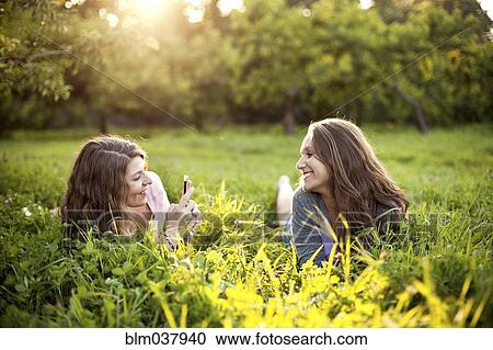 Stock Image - Caucasian women laying in rural field. Fotosearch