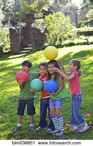 Stock Image - Children playing with balls in grass. Fotosearch