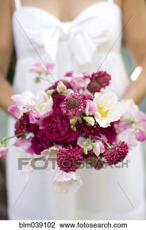 Stock Image - Close up of bride holding bouquet of flowers. Fotosearch