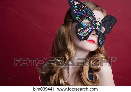 Stock Image - Close up of Caucasian girl wearing butterfly mask. Fotosearch