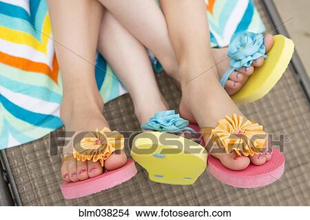 Close up of Caucasian girls wearing flipflops on lawn chair View Large Photo Image Picture - Close up of Caucasian girls wearing flipflops on lawn chair. Fotosearch