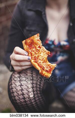 Picture - Close up of Caucasian woman eating pizza outdoors. Fotosearch