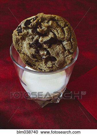 Stock Image - Close up of cookie in glass of milk. Fotosearch