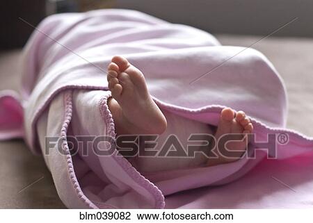 Stock Image - Close up of feet of baby girl in blanket. Fotosearch