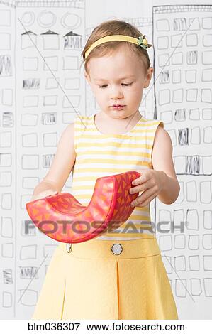 Stock Photo - Close up of girl examining toy. Fotosearch