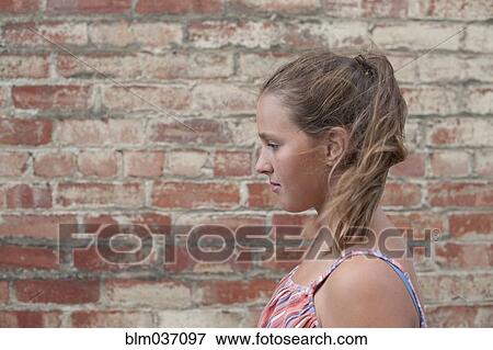Stock Photo - Close up of girl near brick wall. Fotosearch