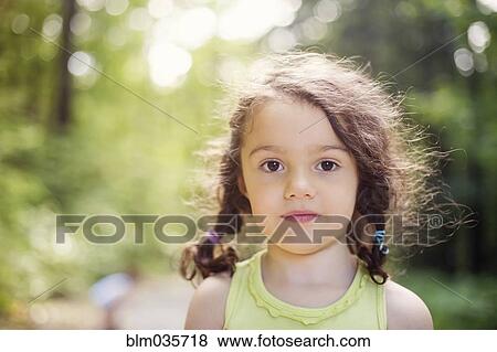 Stock Photo - Close up of girl standing in forest. Fotosearch