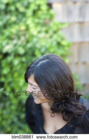 Stock Image - Close up of laughing woman in backyard. Fotosearch