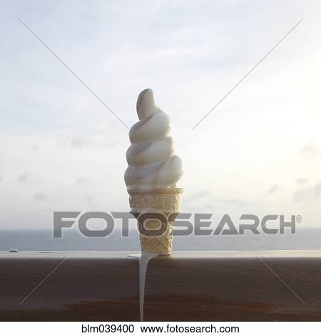 Stock Image - Close up of melting ice cream cone on banister. Fotosearch