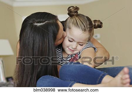 Stock Photo - Close up of mother kissing cheek of daughter. Fotosearch