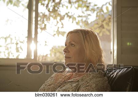 Close up of older woman sitting near window View Large Photo Image Stock Image - Close up of older woman sitting near window. Fotosearch