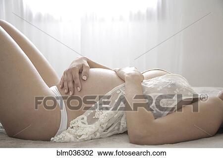 Stock Image - Close up of pregnant woman holding belly. Fotosearch