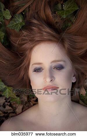 Stock Photo - Close up of serious Caucasian woman laying in leaves. Fotosearch