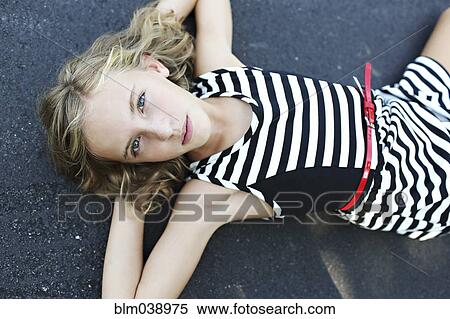 Stock Photography - Close up of serious girl laying on pavement. Fotosearch