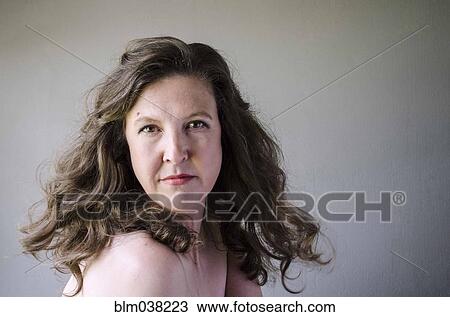 Stock Image - Close up of serious woman twirling hair. Fotosearch