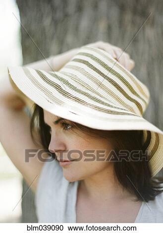 Stock Image - Close up of serious woman wearing sun hat. Fotosearch