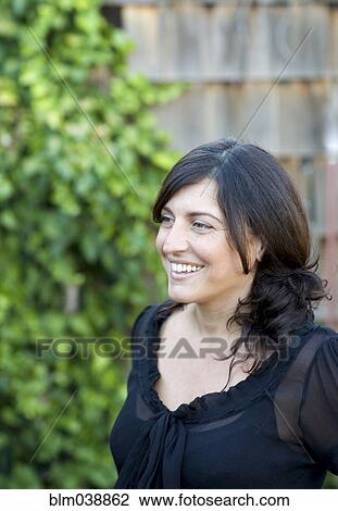 Stock Image - Close up of smiling woman in backyard. Fotosearch
