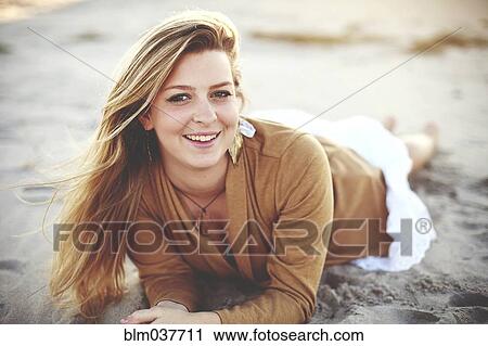 Stock Image - Close up of smiling woman laying on beach. Fotosearch