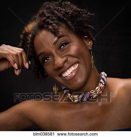 Stock Image - Close up of smiling woman wearing shell necklace. Fotosearch