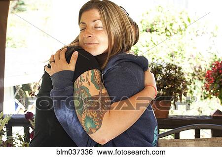 Stock Photograph - Close up of smiling women hugging. Fotosearch