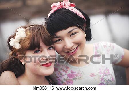 Stock Photograph - Close up of smiling women hugging. Fotosearch