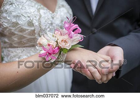 Stock Image - Close up of teenage couple holding hands in prom attire. Fotosearch