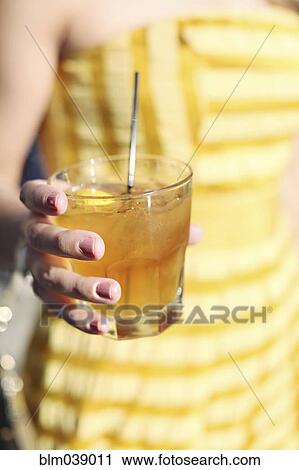 Close up of woman holding yellow cocktail drink View Large Photo Image Stock Image - Close up of woman holding yellow cocktail drink. Fotosearch