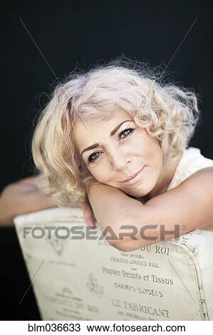 Stock Image - Close up of woman leaning on chair back. Fotosearch