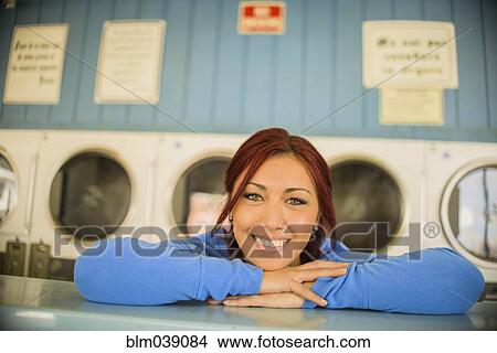 Picture - Close up of woman leaning on counter at laundromat. Fotosearch