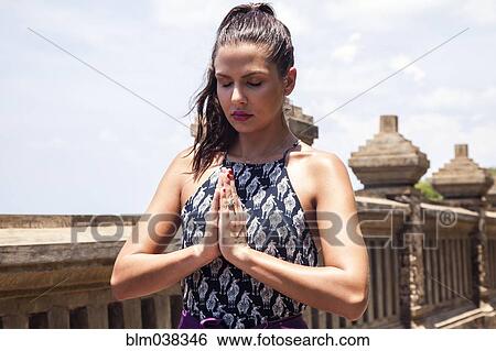 Stock Photograph - Close up of woman meditating by wall. Fotosearch