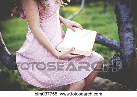 Stock Photo - Close up of woman reading book in tree. Fotosearch