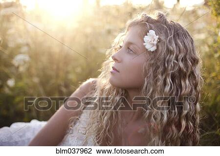 Close up of woman wearing flower in her hair in grass View Large Photo Image Stock Image - Close up of woman wearing flower in her hair in grass. Fotosearch