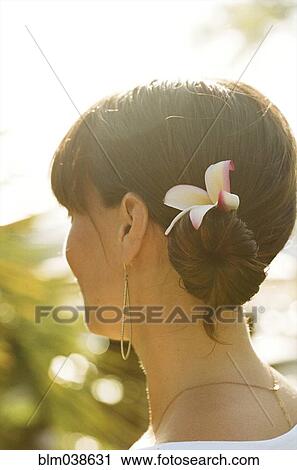Stock Image - Close up of woman wearing flower in her hair. Fotosearch