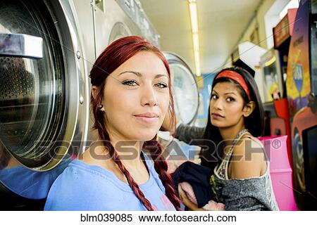 Stock Photography - Close up of women washing clothes at laundromat. Fotosearch