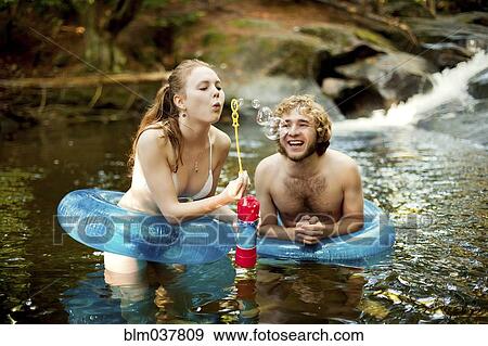 Couple blowing bubbles in forest river View Large Photo Image Stock Photo - Couple blowing bubbles in forest river. Fotosearch