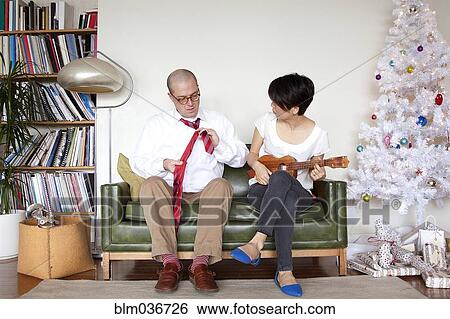 Stock Photograph - Couple enjoying gifts near Christmas tree. Fotosearch