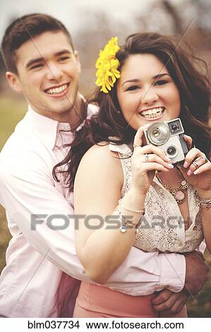 Picture - Couple hugging and taking instant photographs. Fotosearch