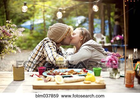 Stock Photo - Couple kissing at picnic table in forest. Fotosearch