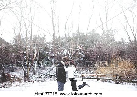 Stock Photo - Couple kissing in snowy rural field. Fotosearch