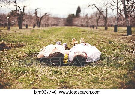 Stock Image - Couple laying on dirt path in vineyard. Fotosearch