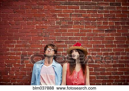 Stock Photo - Couple leaning on brick wall. Fotosearch