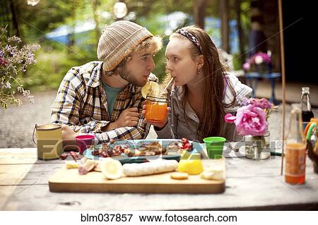 Stock Photo - Couple sharing soda at picnic table in forest. Fotosearch